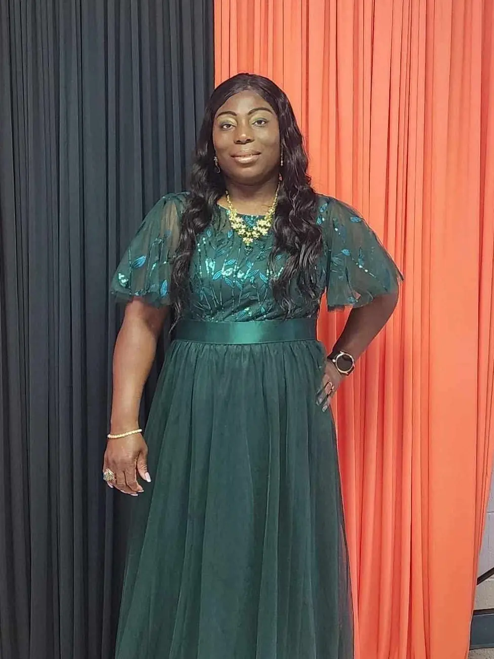 Wosalow, owner of Wosalow Delightful Designs, in a green dress in front of event draping